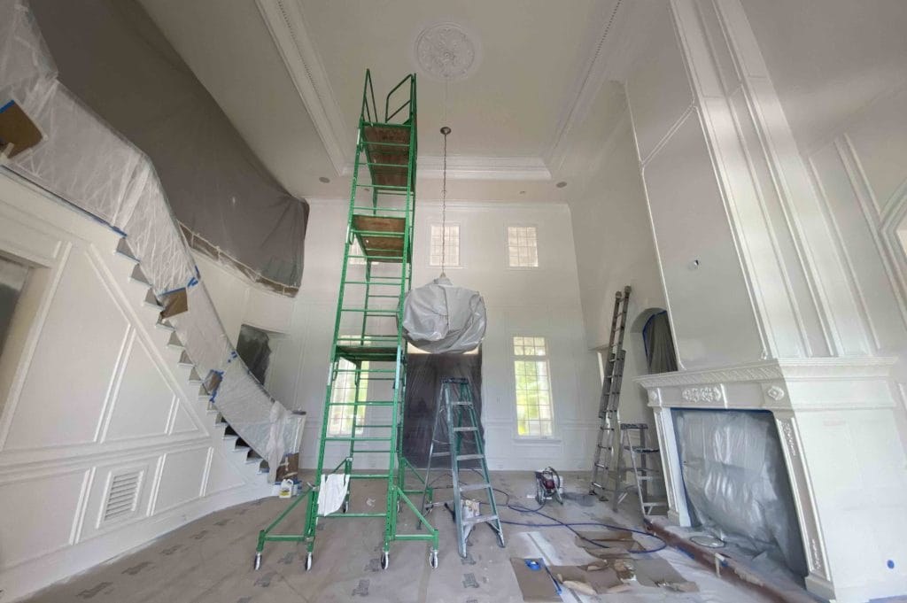 Interior painting in progress in a tall living space, from the Ultimate Services website